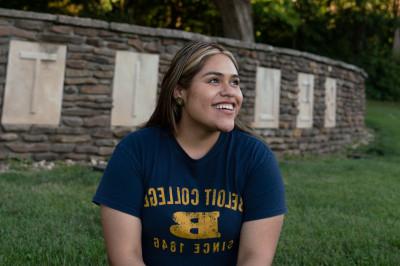 A student in Beloit gear sits in front of the 十大菠菜台子 sign at the southwest side of campus...